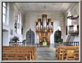 Nach der Kirchenrenovation 2008 ist links neben der Orgel aus symmetrischen Gründen ein Durchgang angedeutet. Die vorher weiss gelassenen Wand wurde mit einer Gittertüre bemalt.